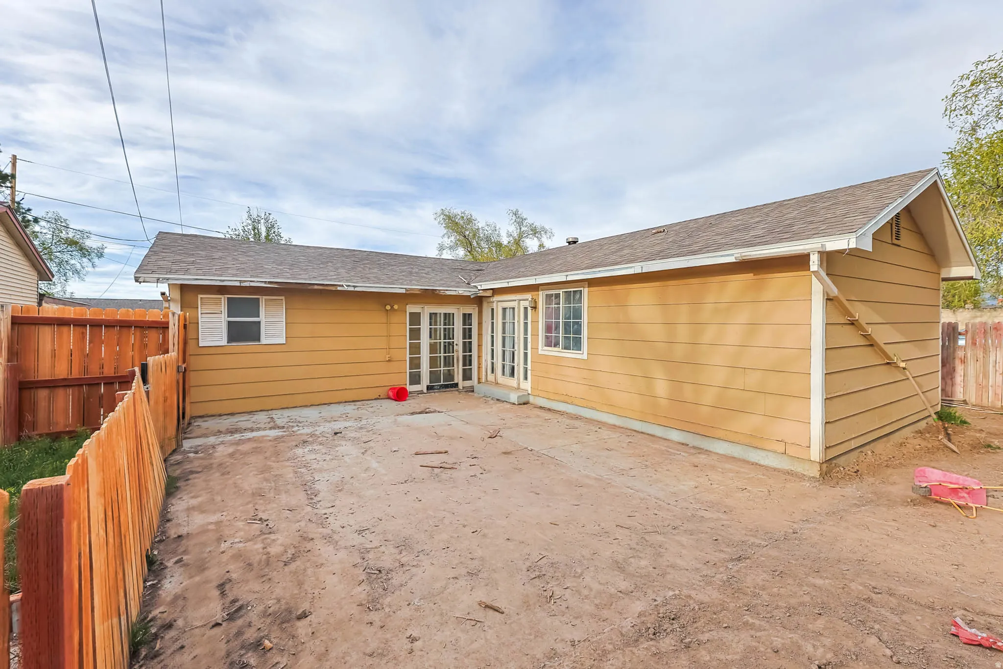 View of front of home with a fenced backyard, a patio, and roof with shingles