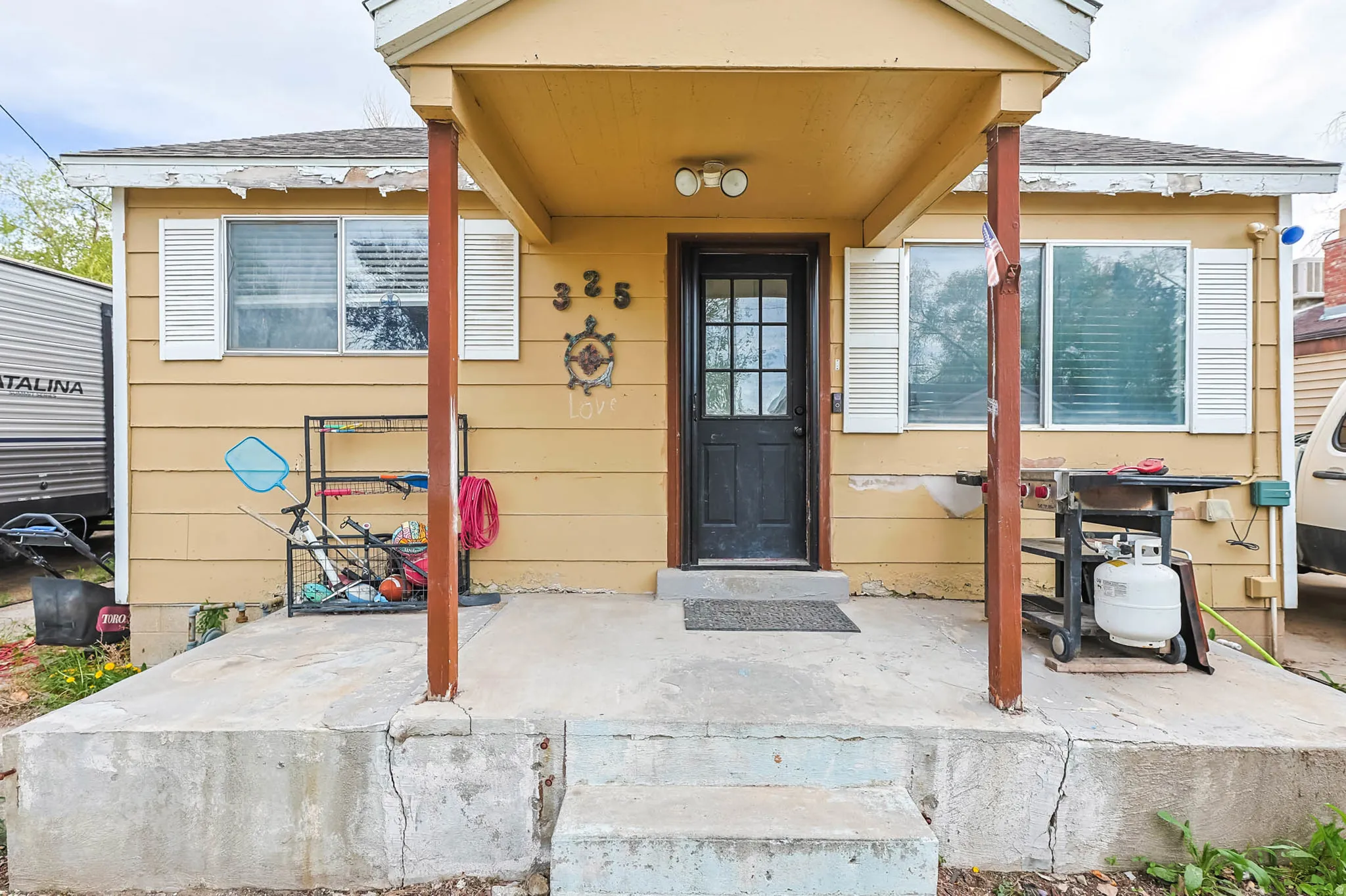 Doorway to property with a porch and a shingled roof