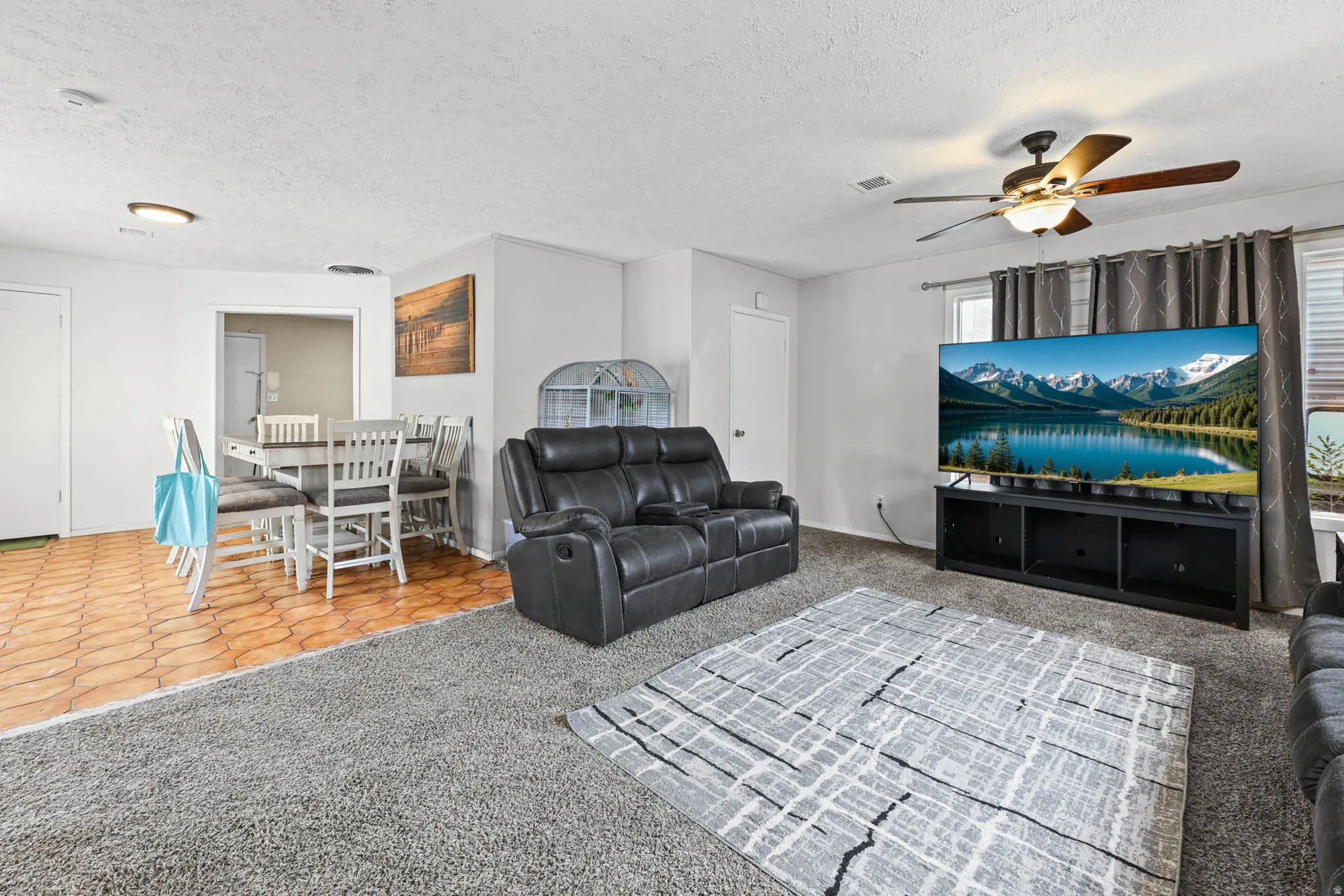 Living room featuring light carpet, a textured ceiling, and ceiling fan