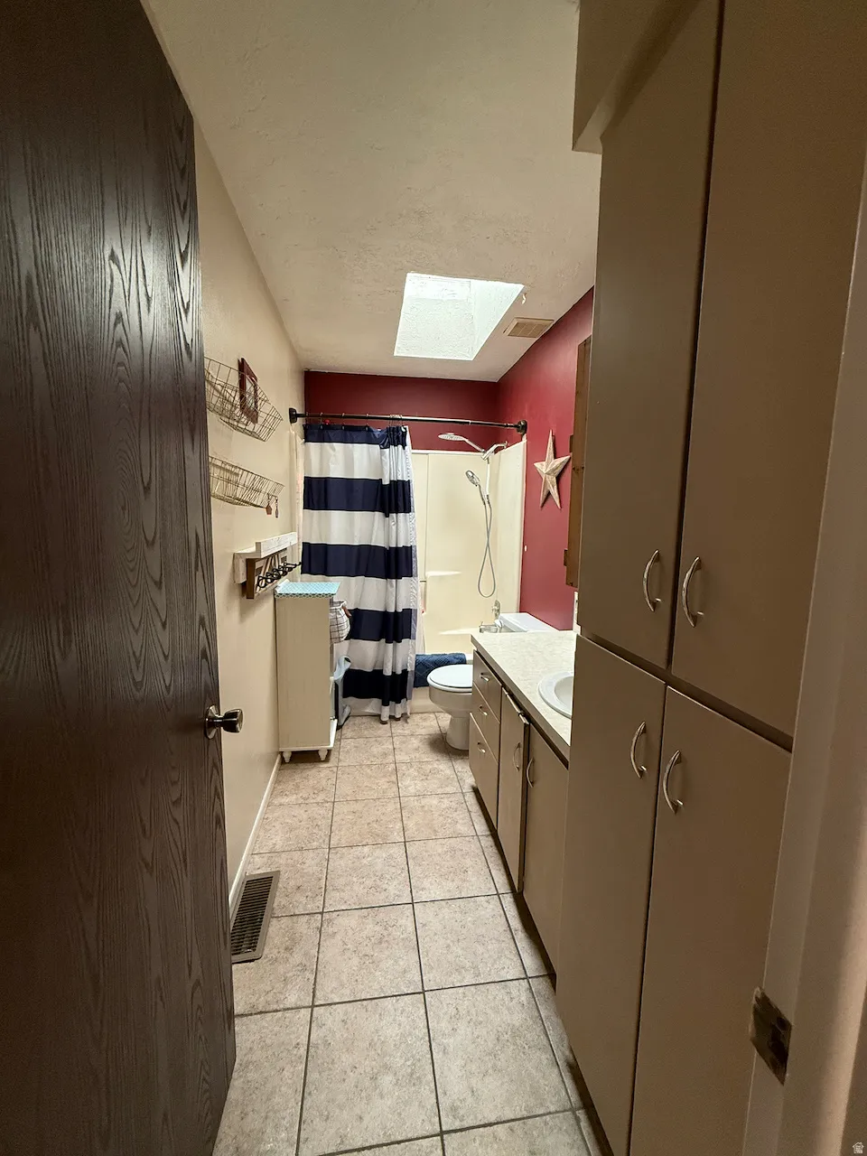 Full bath with vanity, a skylight, light tile patterned flooring, and shower / bath combination with curtain