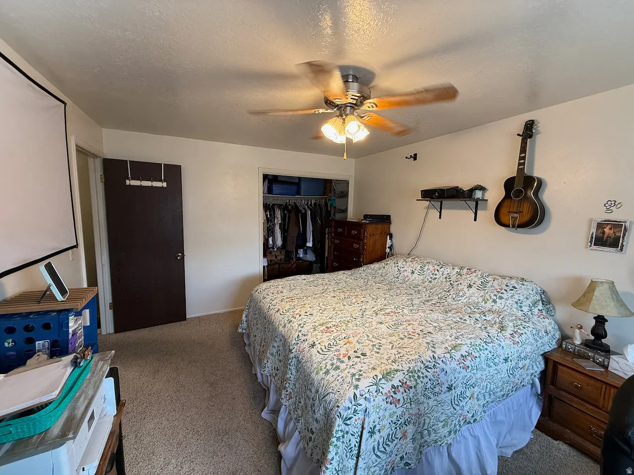 Carpeted bedroom featuring a ceiling fan, a textured ceiling, and a closet
