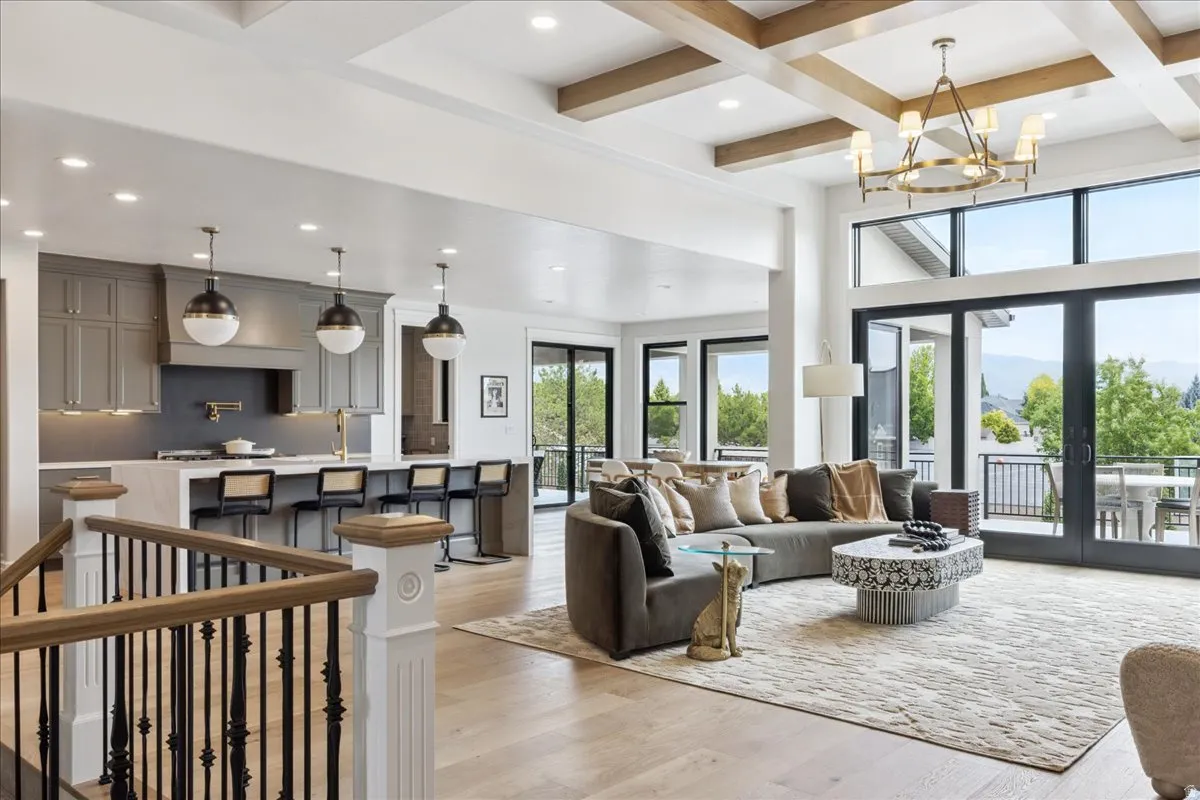 Living room with light wood finished floors, coffered ceiling, french doors, and hanging lights