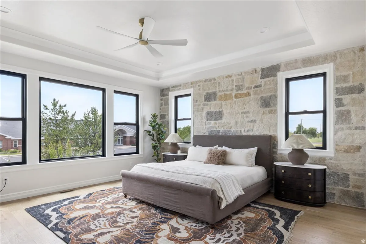 Bedroom featuring multiple windows, light wood-style floors, and a ceiling fan