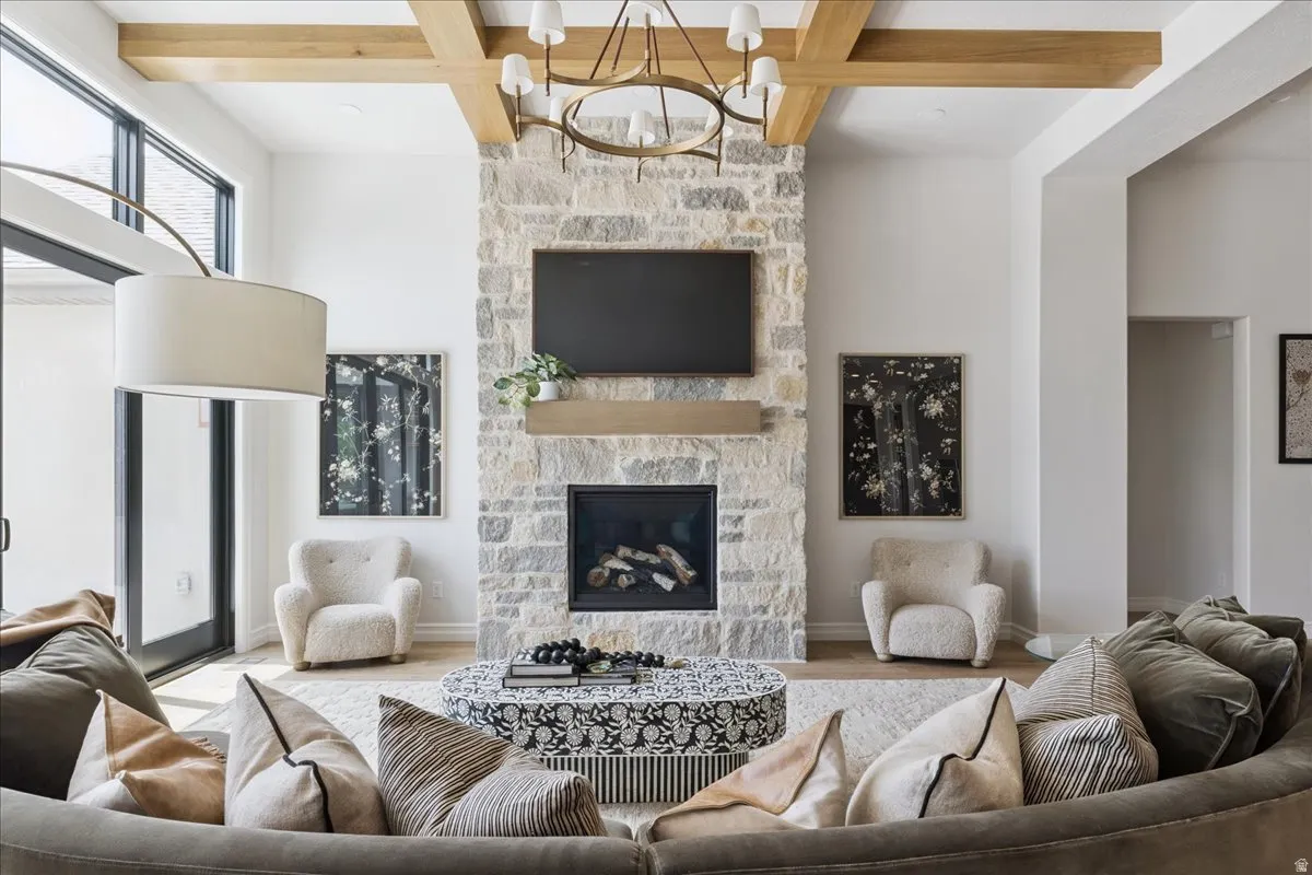 Living room with coffered ceiling, a stone fireplace, wood finished floors, and suspended lighting