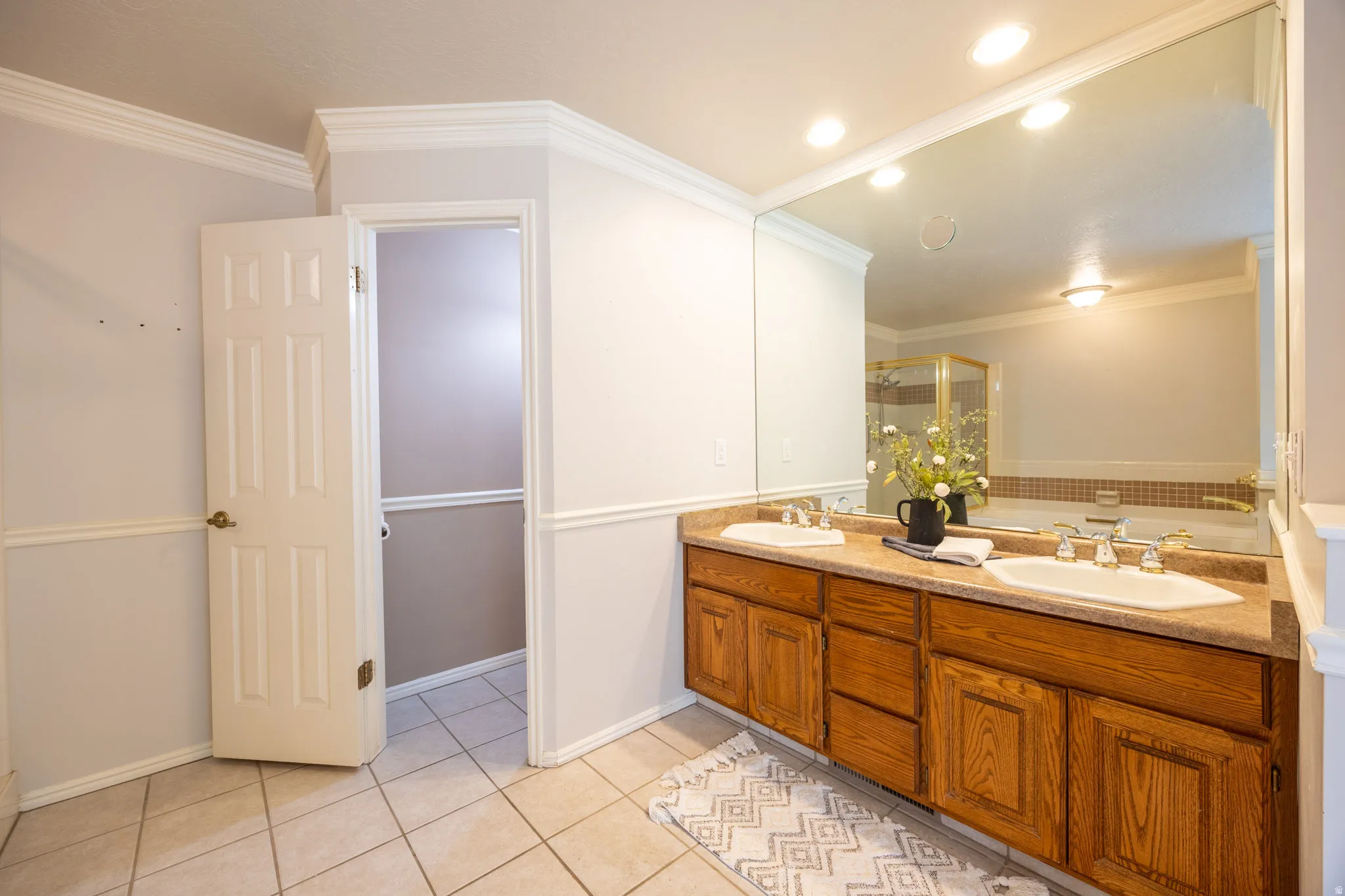 Primary bathroom with double sink vanity, separate water closet and tile flooring.