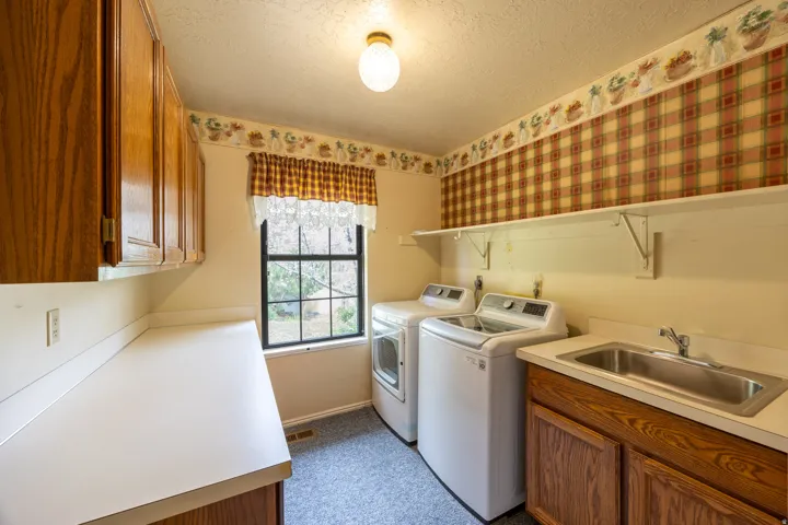 Large laundry room with folding table, sink, and cabinets for storage.