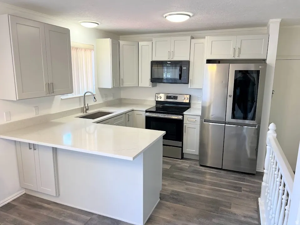 Kitchen featuring stainless steel appliances, a peninsula, dark wood finished floors, white cabinetry, and a textured ceiling