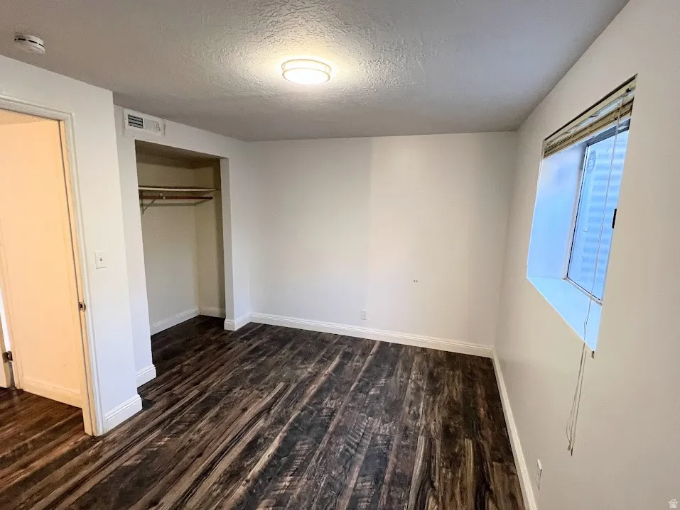Unfurnished bedroom with dark wood finished floors, a closet, and a textured ceiling