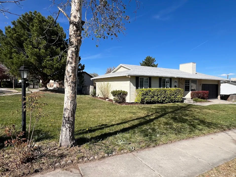 View of front facade featuring an attached garage, a front lawn, a chimney, and covered porch