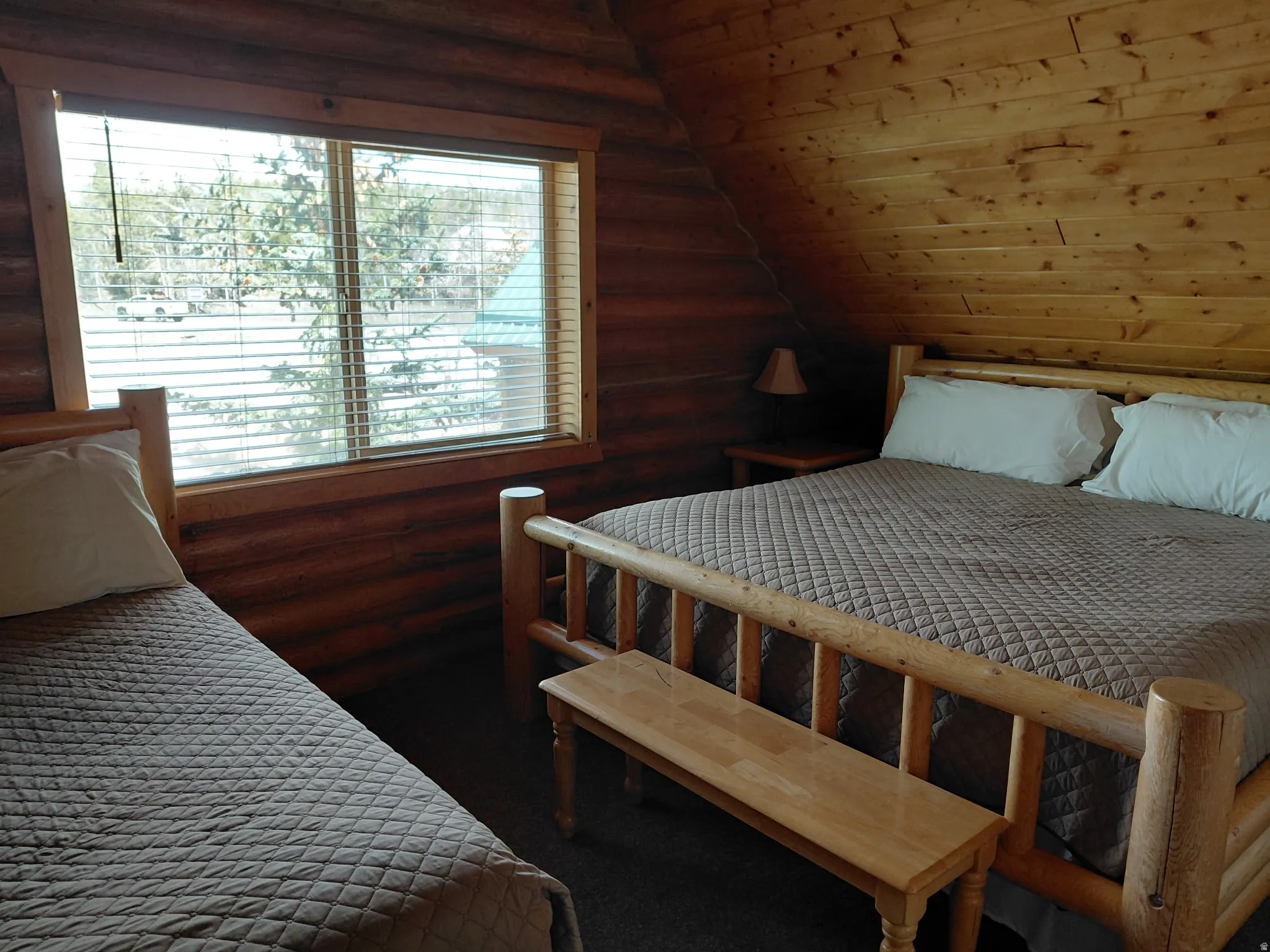 Carpeted bedroom with rustic walls and a vaulted wood ceiling