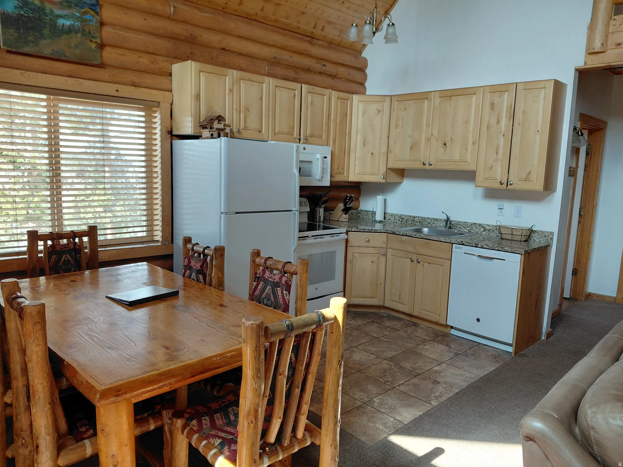 Kitchen featuring light wood finish cabinets, white appliances, rustic walls, a high wooden ceiling, and light colored carpet