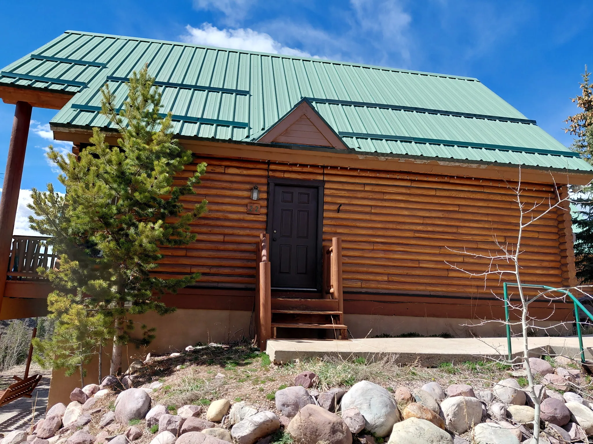 View of front of home featuring entry steps, log siding, and a metal roof