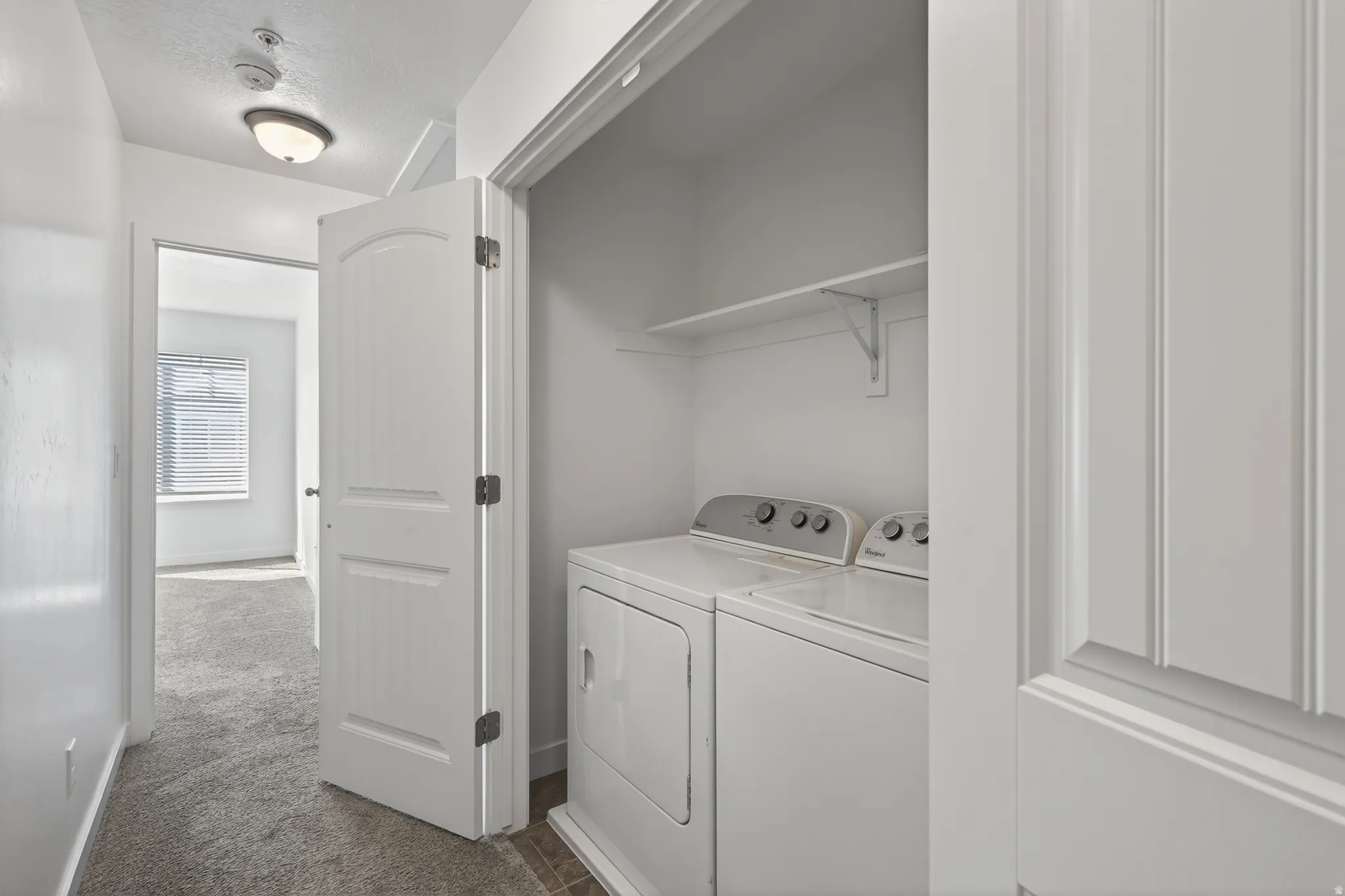 Laundry area with dark colored carpet and separate washer and dryer