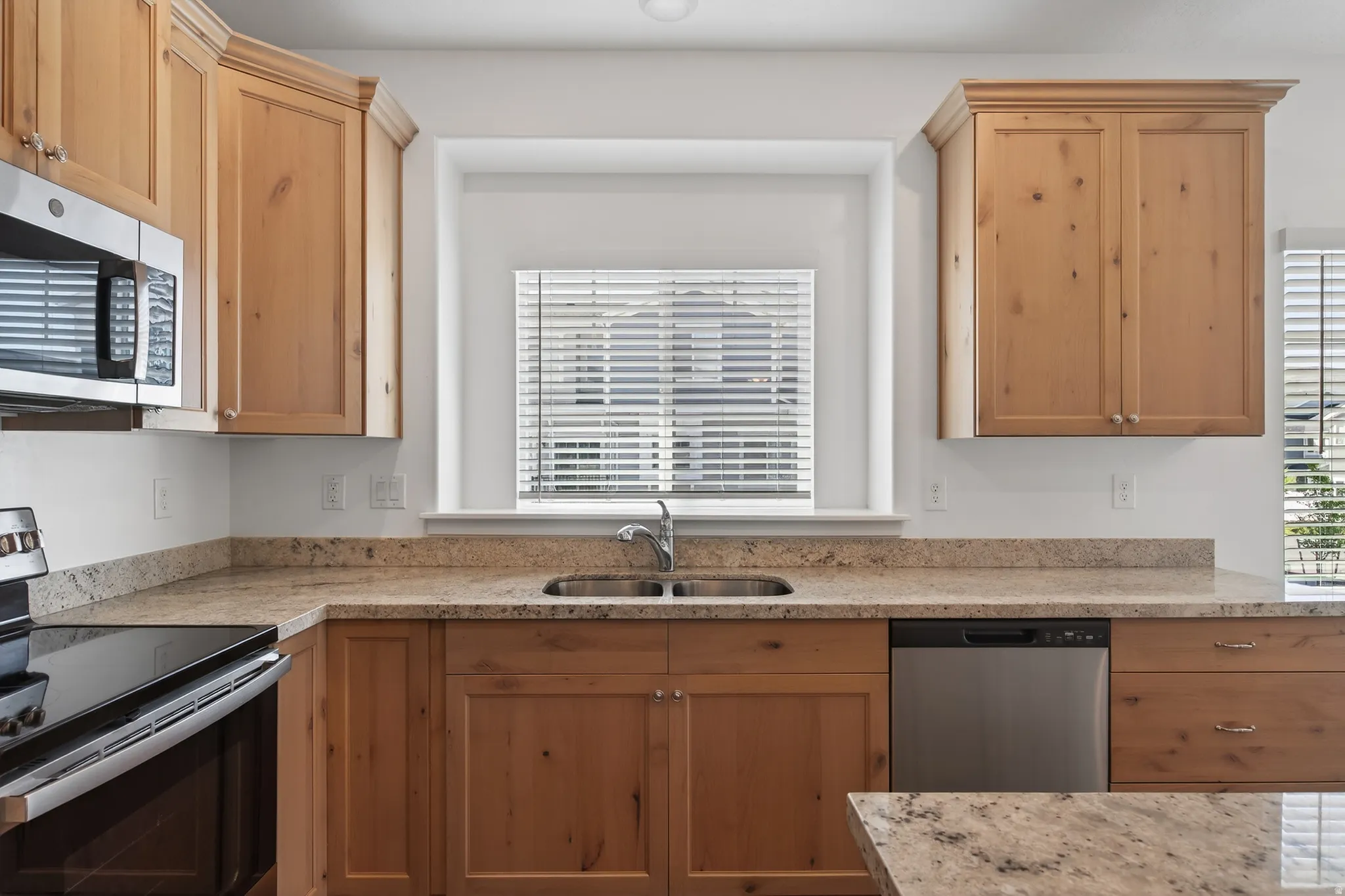 Kitchen featuring stainless steel appliances, plenty of natural light, and light stone countertops