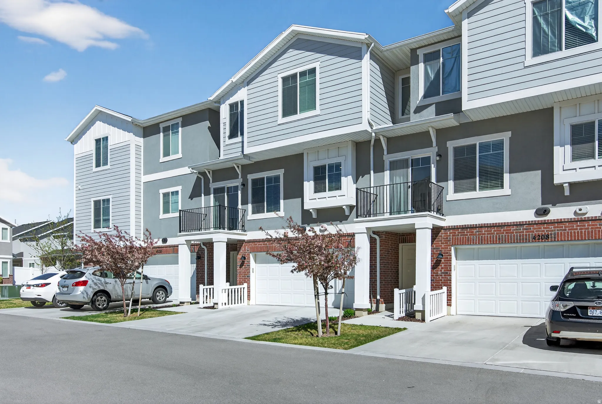 View of front of home featuring a balcony, brick siding, an attached garage, concrete driveway, and a residential view