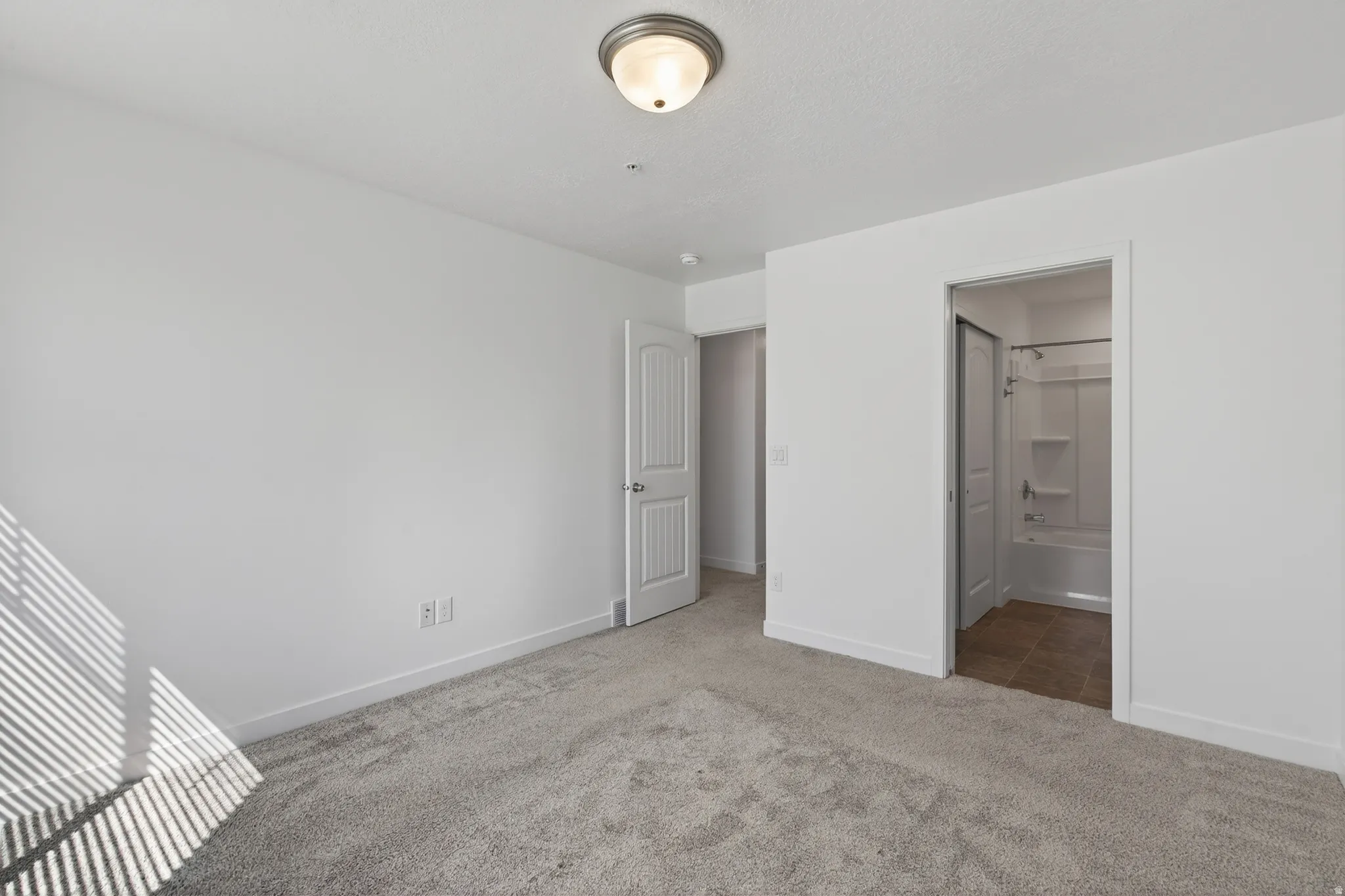 Unfurnished bedroom featuring carpet and ensuite bath