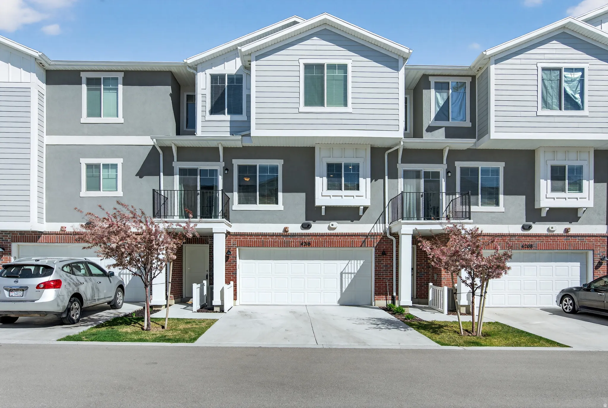 Traditional home with a balcony, driveway, an attached garage, and brick siding
