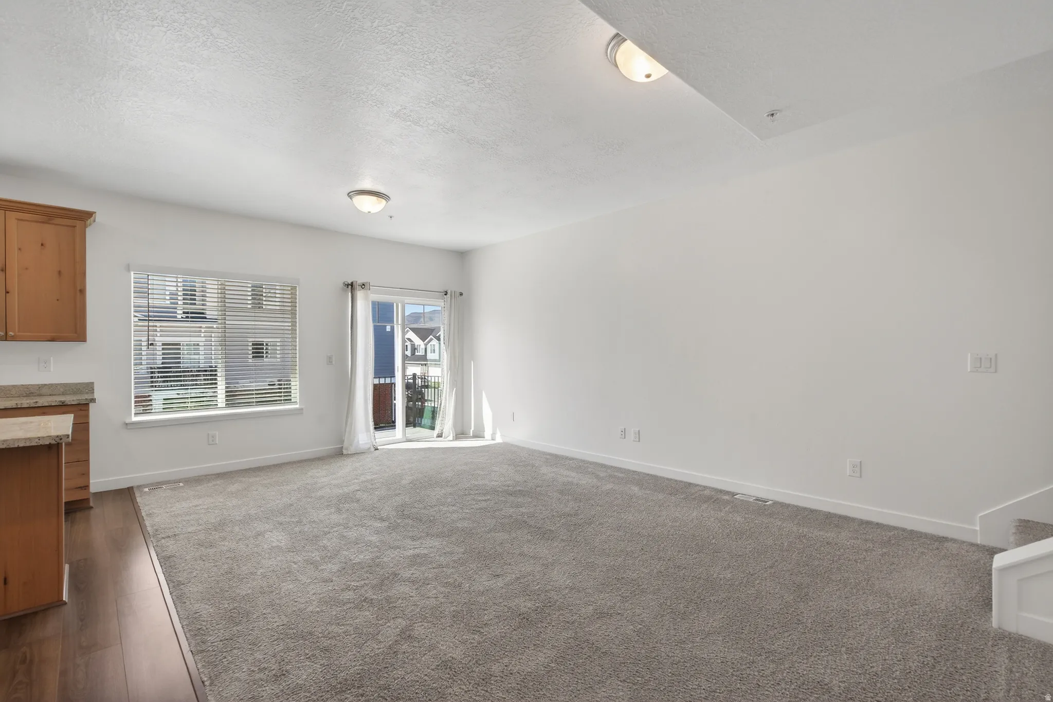 Unfurnished living room featuring a textured ceiling and dark colored carpet