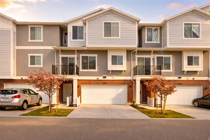 View of front of house with a balcony, brick siding, concrete driveway, a garage, and a residential view