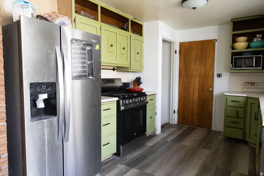 Kitchen featuring green cabinets, stainless steel appliances, light countertops, and dark wood finished floors