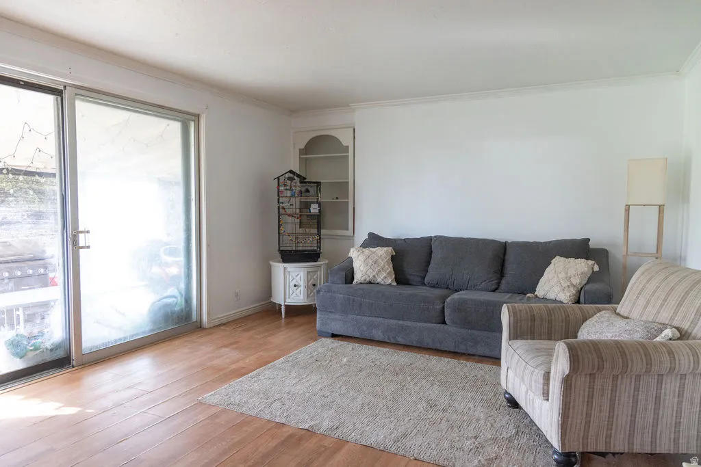 Living area with light wood-type flooring and crown molding