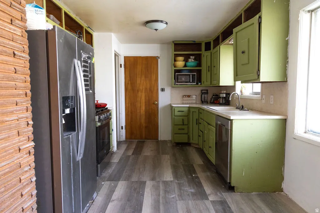 Kitchen featuring green cabinetry, open shelves, stainless steel appliances, and light countertops