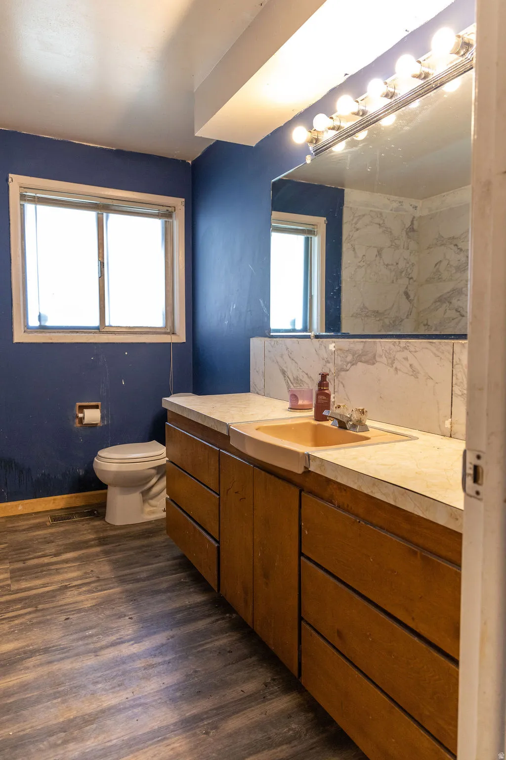 Full bathroom with vanity, dark wood-type flooring, and decorative backsplash