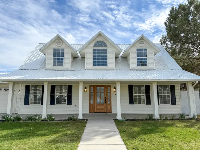 View of front of property featuring covered porch, a front lawn, and a metal roof