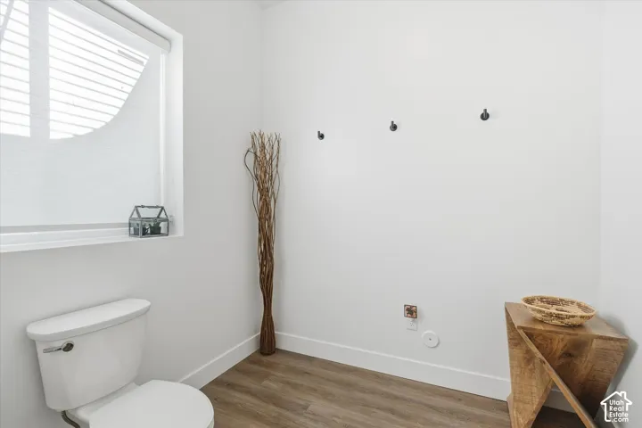 Half bath featuring toilet and wood finished floors