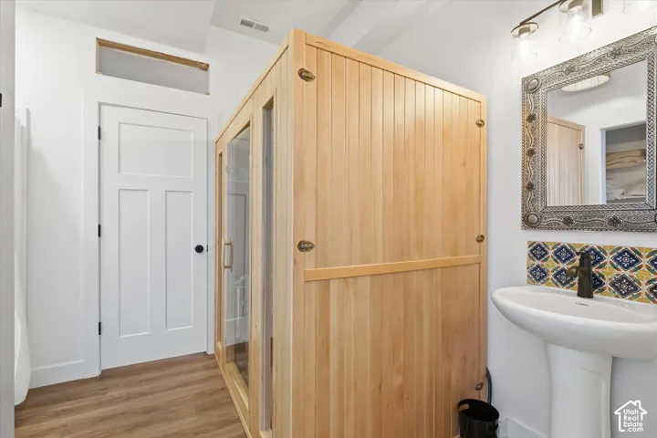 Half bath with wood-style finished floors and tile backsplash