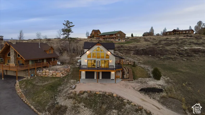 Back of house with dirt driveway, a garage, a chimney, and a balcony