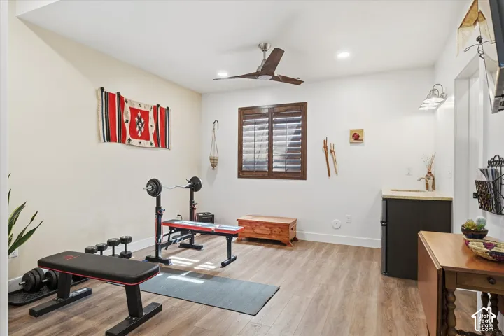 Exercise room with light wood finished floors, a ceiling fan, and recessed lighting