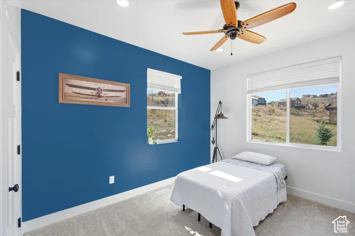 Carpeted bedroom featuring multiple windows, ceiling fan, and recessed lighting