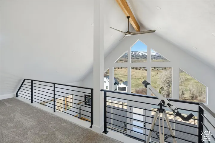 Balcony bonus room featuring ceiling fan, carpet floors, beam ceiling, and a mountain view