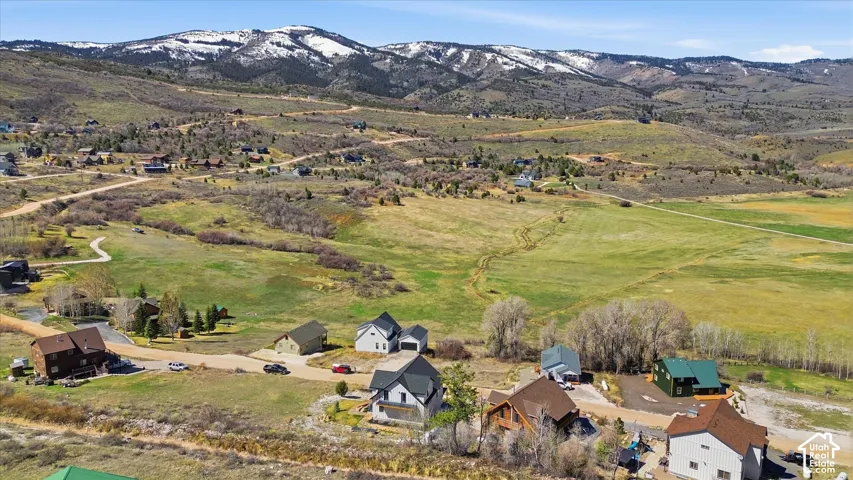 Aerial view of property and surrounding area with a mountainous background and nearby suburban area