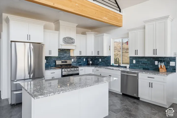 Kitchen with stainless steel appliances, white cabinetry, light stone countertops, and recessed lighting