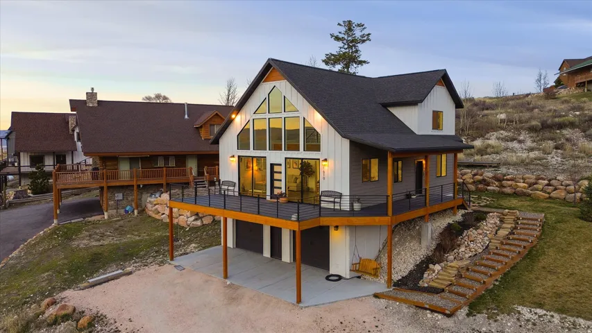 Back of property with a wooden deck, a patio area, driveway, and an attached garage