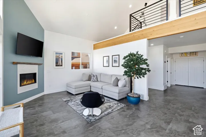 Living area with a glass covered fireplace, concrete floors, lofted ceiling, and recessed lighting