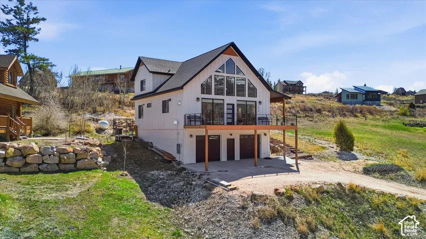 Rear view of house featuring an attached garage, driveway, a patio area, and a residential view