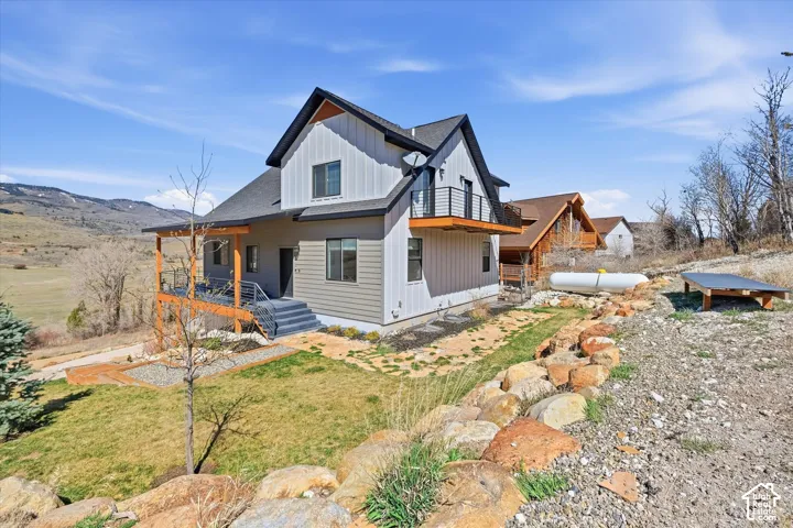 Rear view of house with a yard, board and batten siding, a shingled roof, and a mountain view