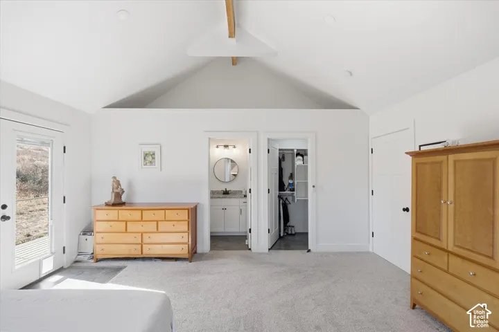 Bedroom featuring access to outside, light carpet, a spacious closet, beam ceiling, and ceiling fan