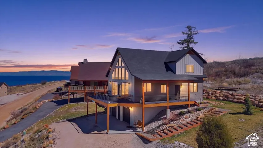 Back of property at dusk with a patio, an attached garage, driveway, roof with shingles, and a mountain view