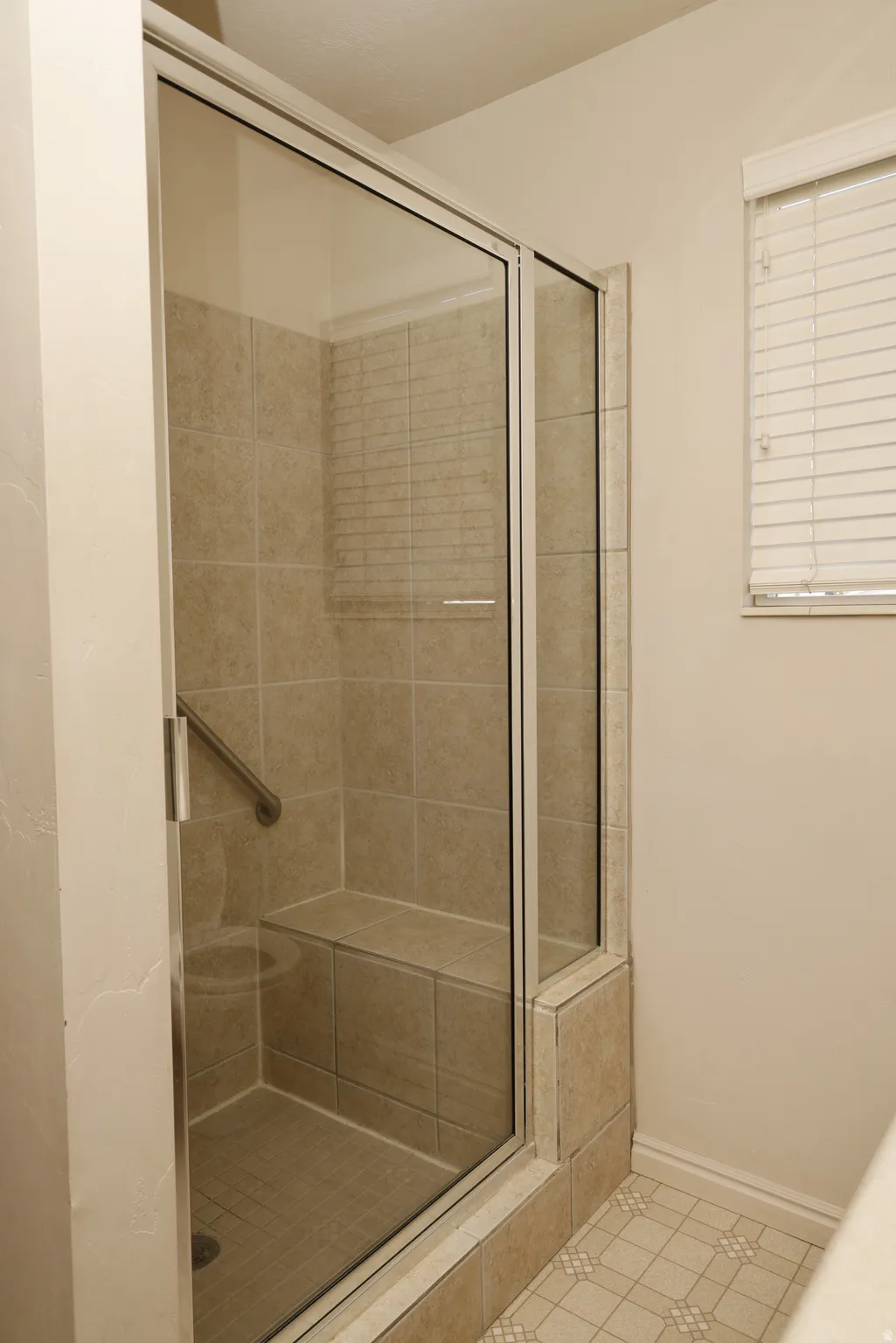 Bathroom featuring a shower stall and light tile patterned flooring