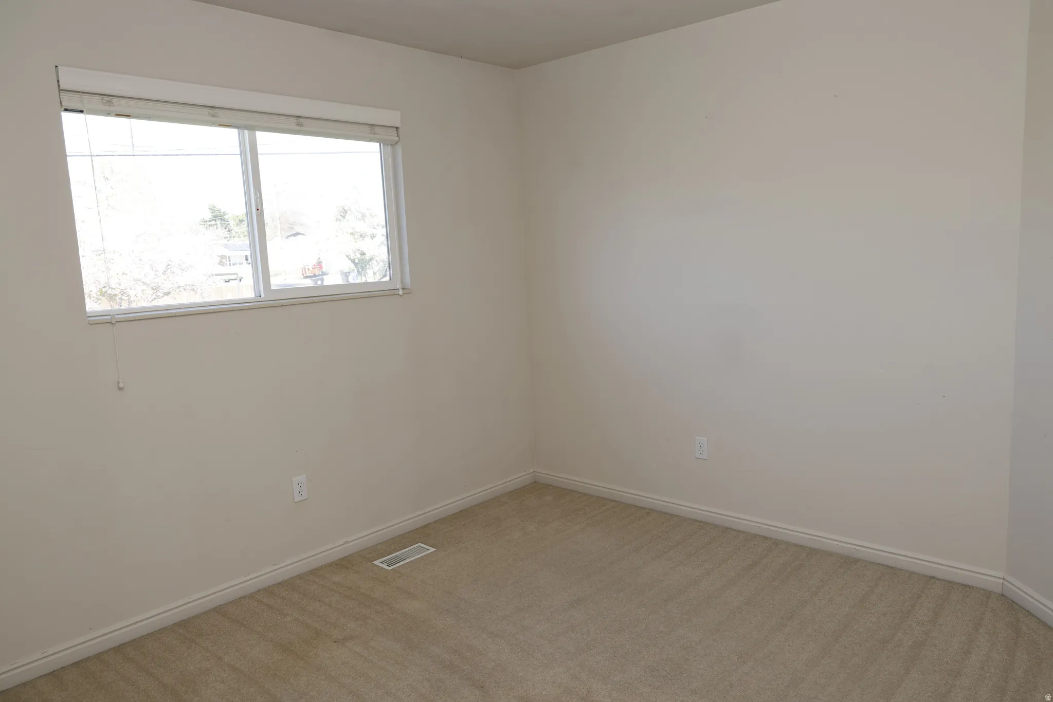 Unfurnished room featuring light carpet and baseboards