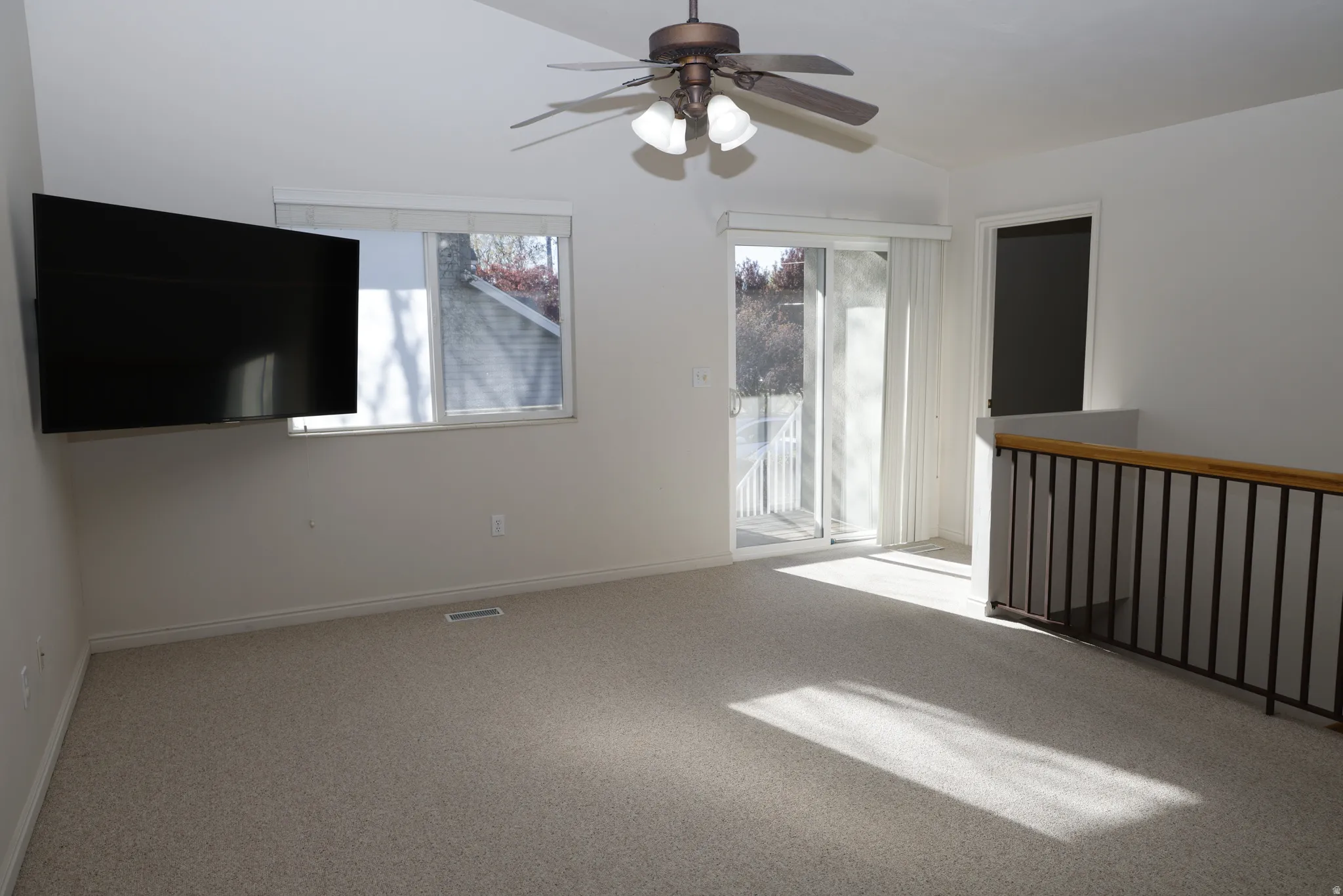 Unfurnished room with a ceiling fan, carpet flooring, and vaulted ceiling