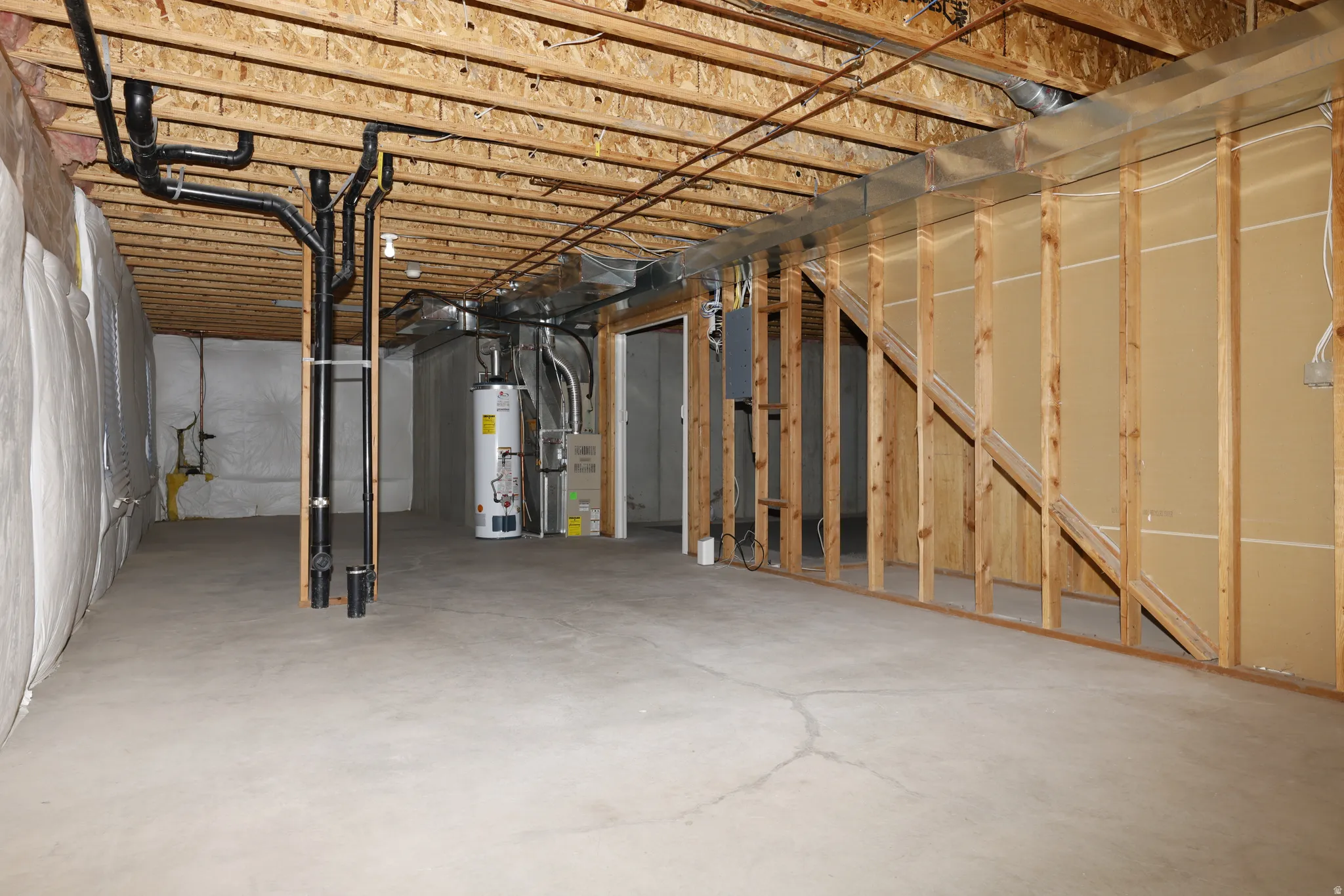 Unfinished below grade area featuring water heater and heating unit