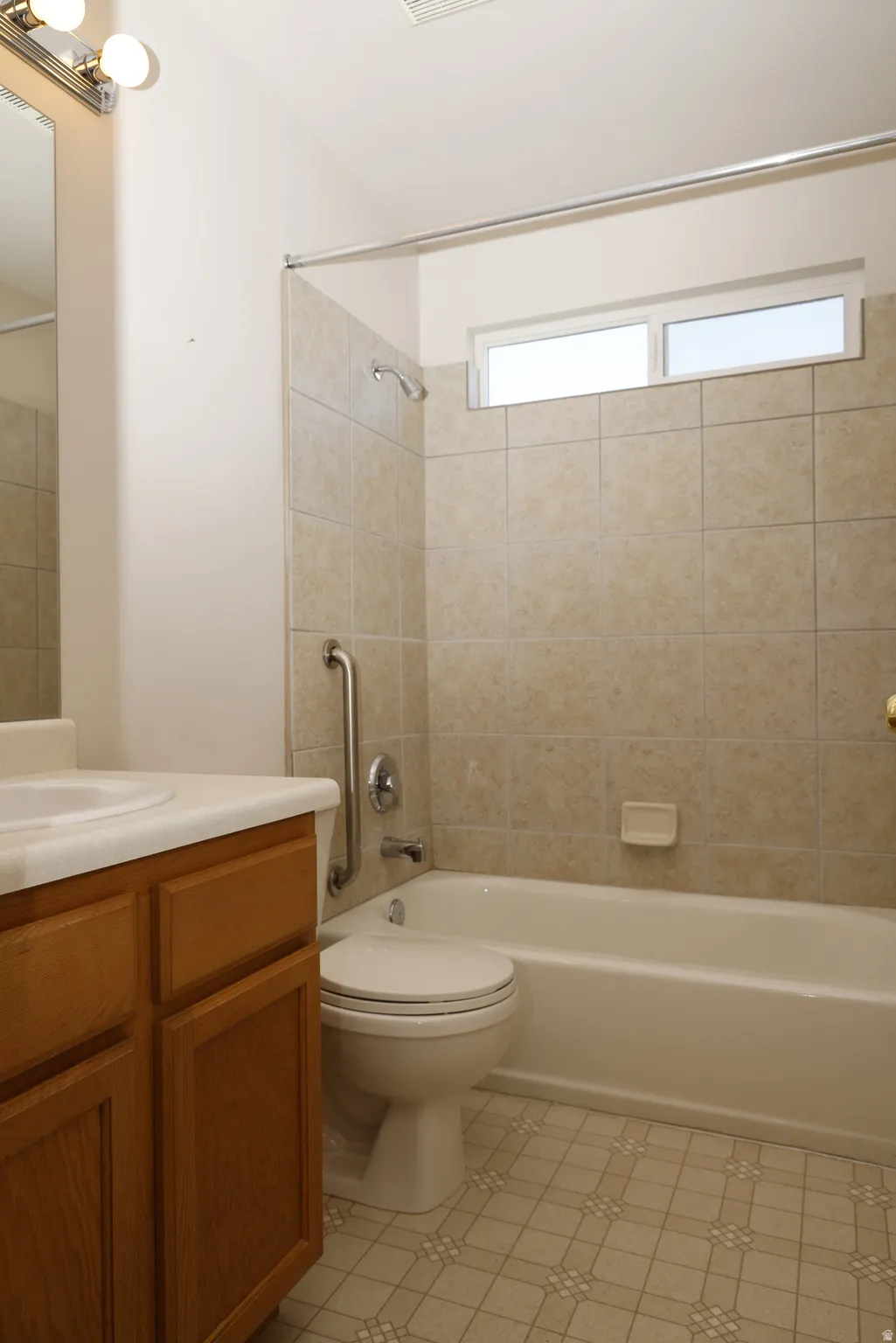 Bathroom featuring vanity, shower / washtub combination, and light tile patterned flooring