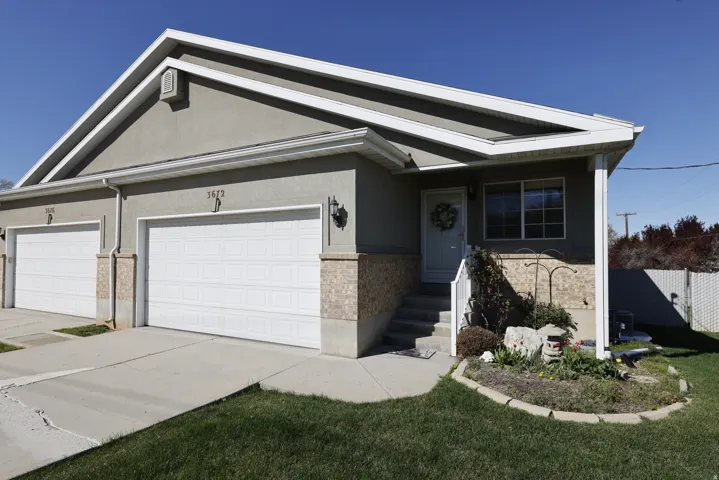View of front facade featuring stucco siding, a garage, concrete driveway, and brick siding