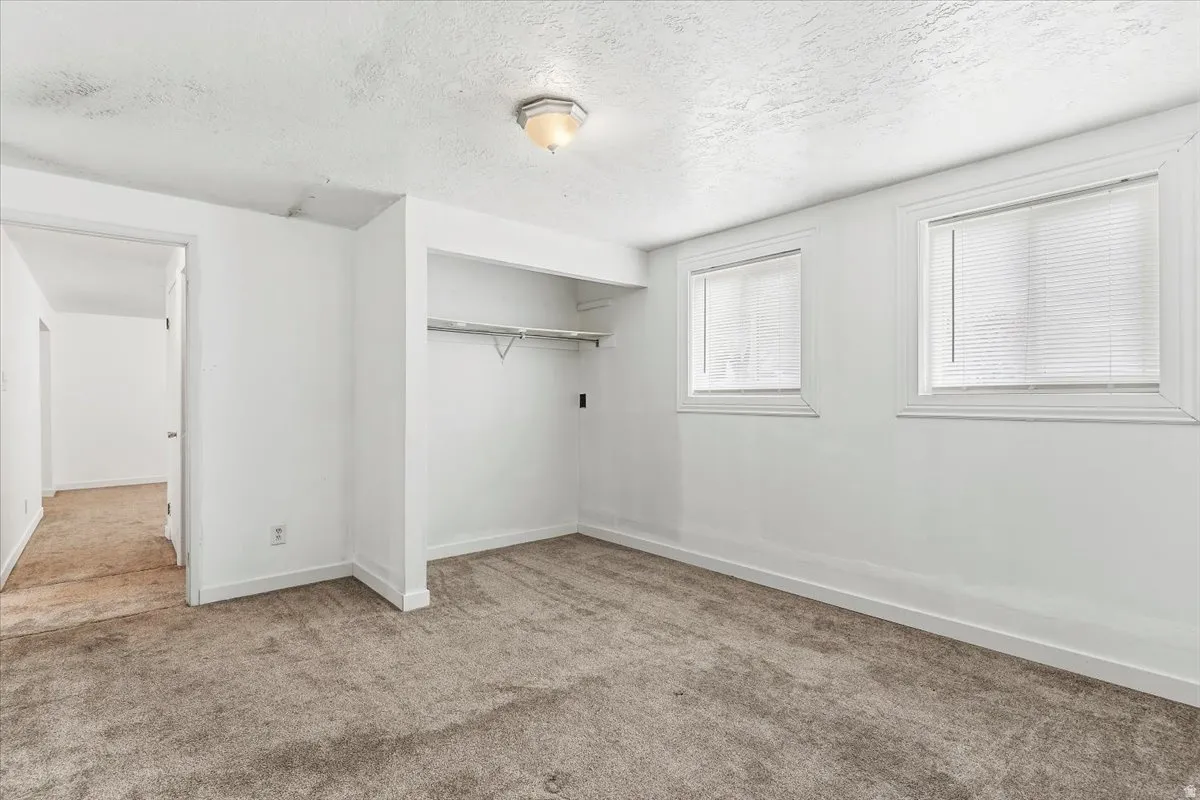 Unfurnished bedroom featuring carpet, a textured ceiling, and a closet