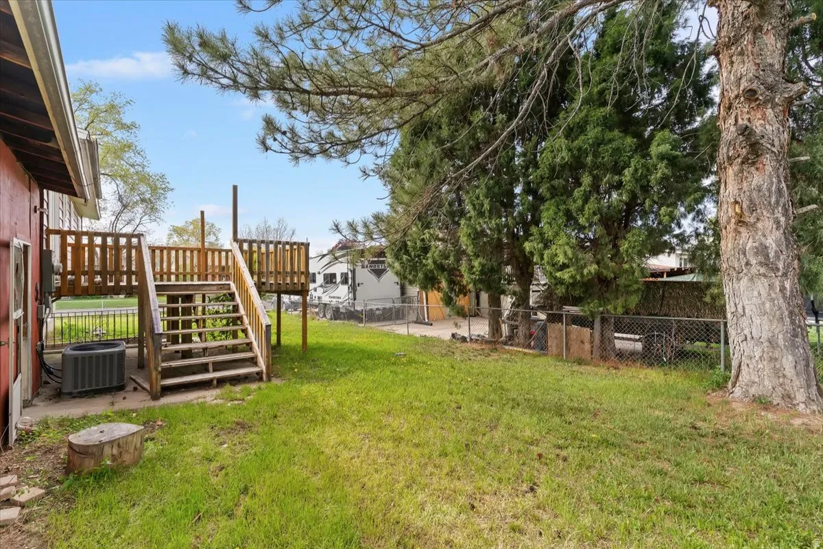 Fenced backyard featuring a wooden deck and a patio
